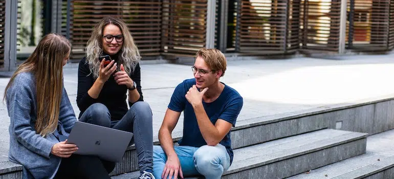 three students sitting on a stairs and talking about moving out of New Jersey