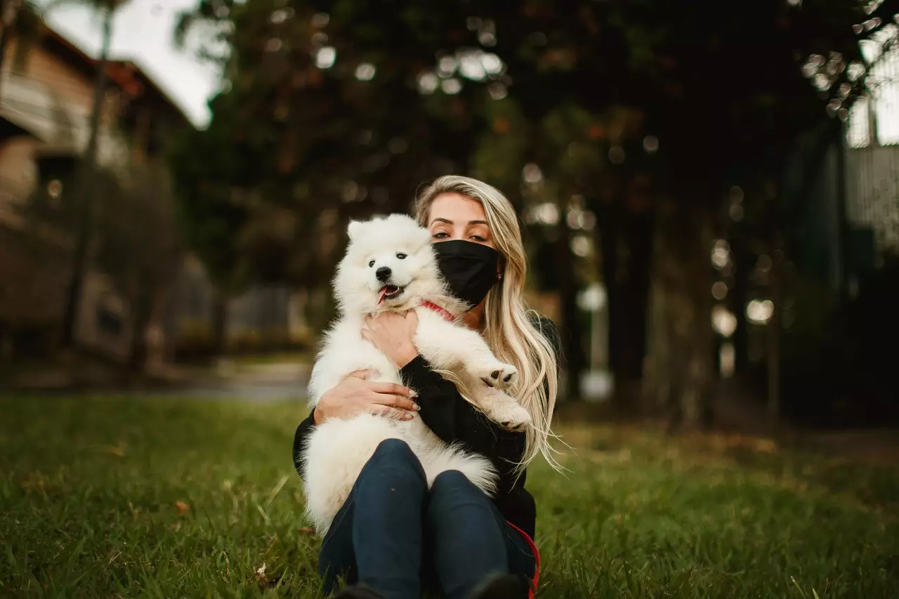 a woman in black outfit hugging her white dog
