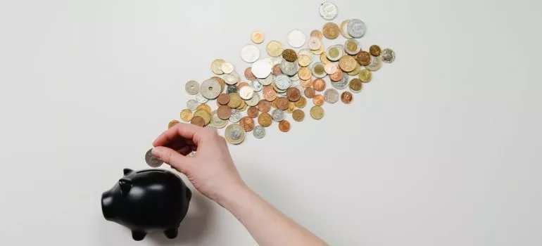 A person is putting coin in a piggy bank