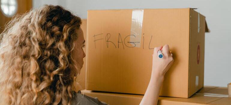 woman is writing fragile on a box