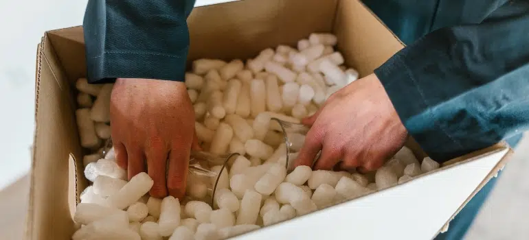 A mover packing glass cups into a box